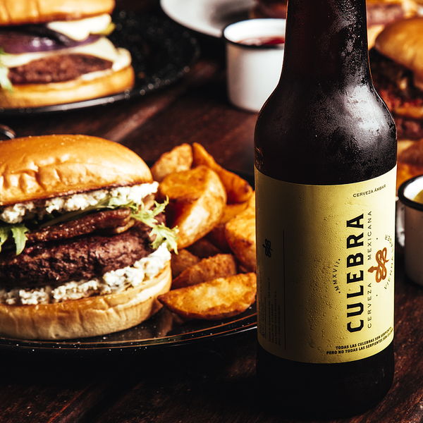 Hamburguesa acompañada de una cerveza artesanal en la mesa de madera