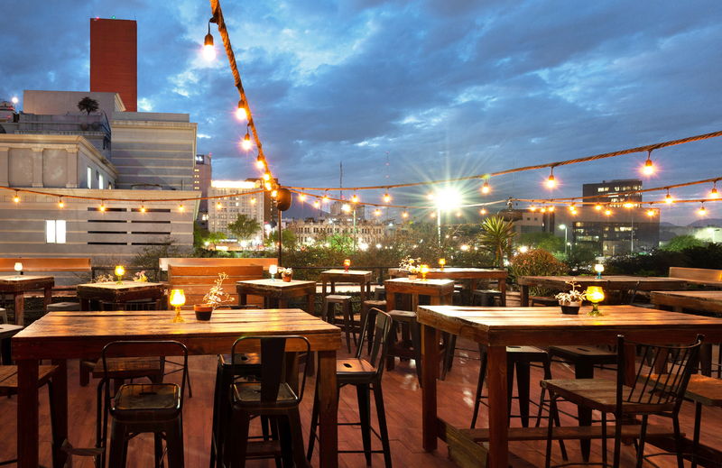 La terraza de noche con los edificios del centro de Monterrey iluminados al fondo
