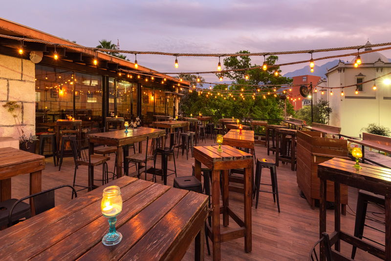 Rincón de la terraza con vegetación y luces cálidas al anochecer
